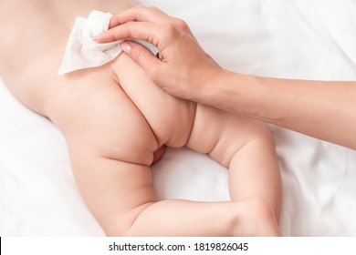 Mother cleaning up her baby's buttocks with wet hankies. mother wipes the baby with a baby wipe. The concept of cleanliness and care.