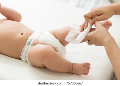 Mother cleaning up and wipes body and leg baby by wet tissue - Shutterstock ID 757830667