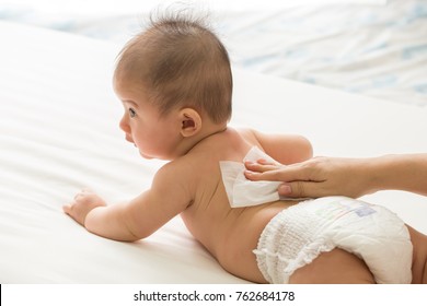 Mother cleaning up and wipes body and leg baby by wet tissue