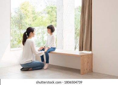 Mother comforting her daughter in the living room - Shutterstock ID 1806504739