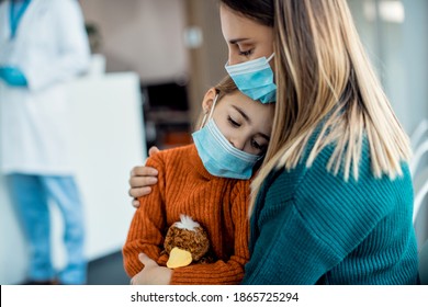 Mother comforting her sad daughter while sitting in waiting room in the hospital and wearing protective face masks.  - Powered by Shutterstock