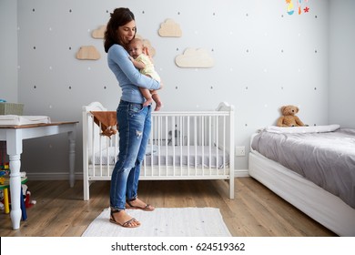Mother Comforting Newborn Baby Son In Nursery