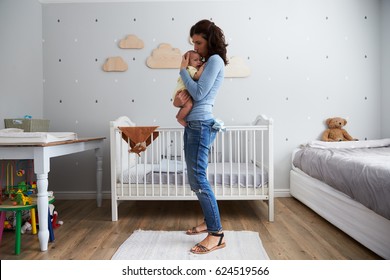 Mother Comforting Newborn Baby Son In Nursery