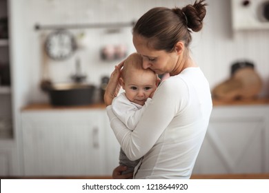 Mother Comforts A Sad Baby, Mom Holds Her Son In Her Arms In A Real Bright Interior.