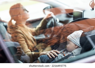 Mother Concentrating On Driving Family Car Running Errands While Her Baby Sleeps In Infant Car Seat By Her Site.