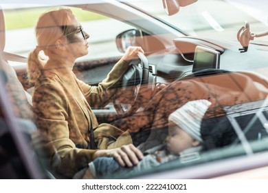 Mother Concentrating On Driving Family Car Running Errands While Her Baby Sleeps In Infant Car Seat By Her Site.