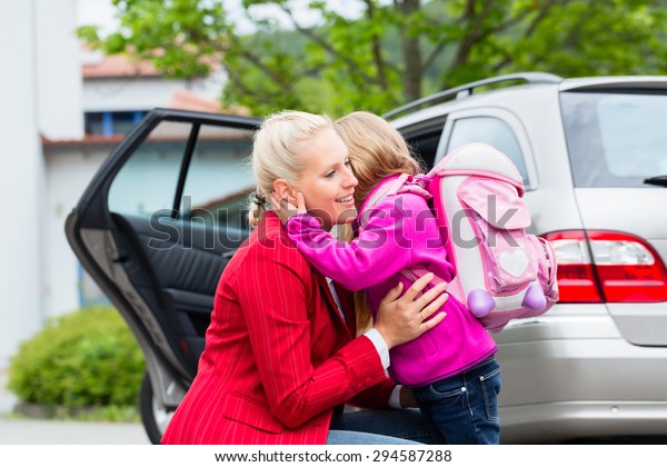 Mother consoling daughter on\
first day at school, the kid being a bit afraid of what may lay\
ahead