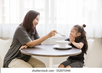 Mother convince daughter to eat food at window side