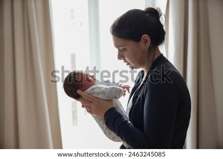 Similar – Mother giving bottle to her newborn