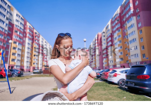 mother cuddles her child in the courtyard of a\
multi-storey building.