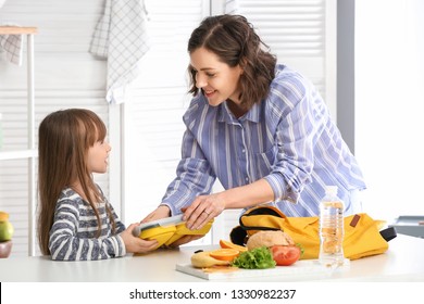 Mother with cute daughter preparing school lunch at home - Powered by Shutterstock