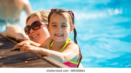 mother with a cute daughter sitting by the pool