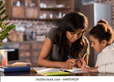Mother and cute little daughter sitting at table and doing homework together at home, homework help concept - Shutterstock ID 644959039