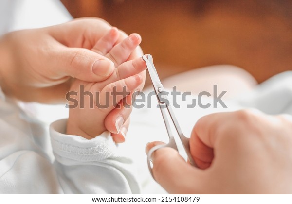 mother cuts baby\'s fingernails\
with special children\'s scissors. close up. manicure for newborns.\
