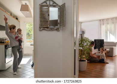 Mother Dancing In The Kitchen And Father Doing School Lessons With Daughter