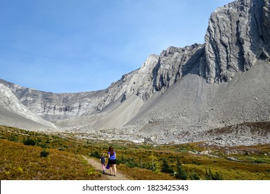 A Mother And Daugher Hiking A Beautiful Trail Above The Treeline With A Huge Mountain In The Background During A Sunny Day In Autumn, Along The Ptarmigan Cirque Trail In Kananaskis, Alberta, Canada