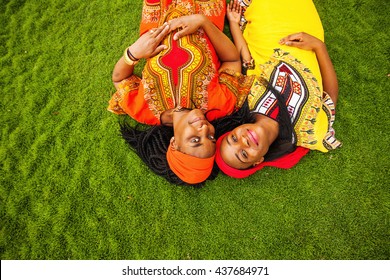 mother and daughter of African ethnicity lying down on a grass