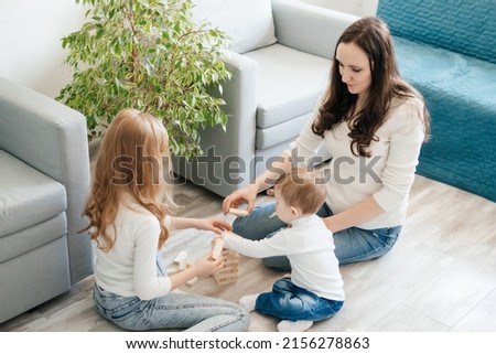 mother with daughter and baby son playing a game of django on the floor. High quality photo