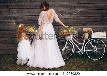 Mother with daughter in beautiful dresses by the bicycle
