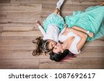 Mother and daughter beautiful and happy in turquoise skirts lie on laminate flooring home top view