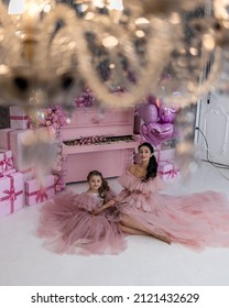 mother and daughter are beautiful in lush, airy pink dresses, near a pink piano, a piano with a huge number of flowers, a lot of flowers, in a festive mood they congratulate everyone on Valentine's Da