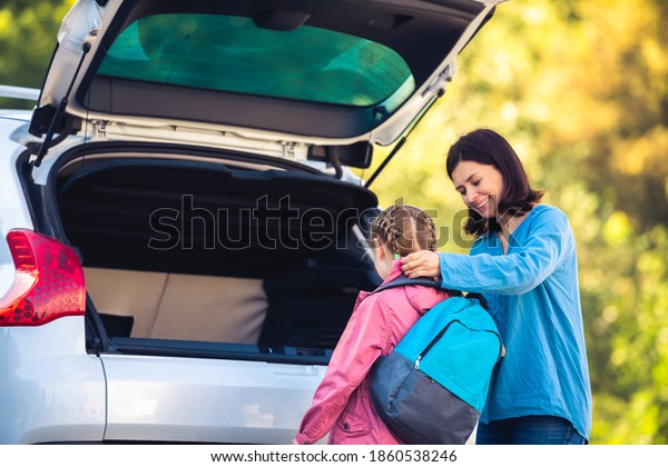 Mother and daughter before lessons at school
near open car trunk
outdoors