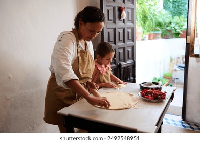 Mother and daughter bonding in the kitchen while making homemade pizza. The scene captures family togetherness and the joy of cooking with fresh ingredients. - Powered by Shutterstock