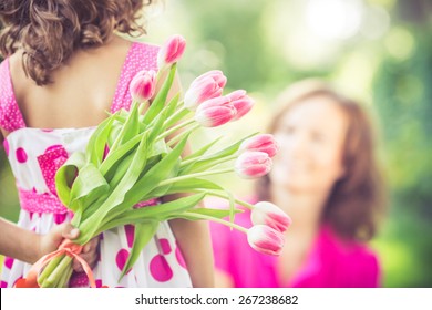 Mother and daughter with bouquet of flowers against green blurred background. Spring family holiday concept. Mother's day - Powered by Shutterstock