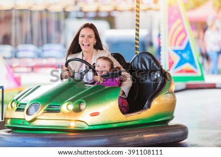 Mother and daughter in bumper car at fun fair