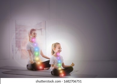 Mother And Daughter With Chakra Points Practicing Yoga In Studio. Healing Energy 