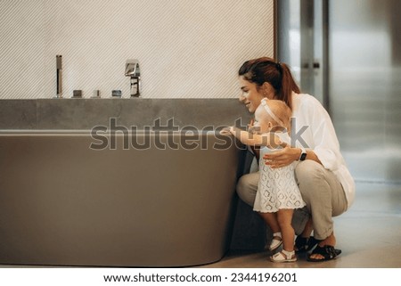 mother and daughter choose a bathtub in a sanitary ware store.
