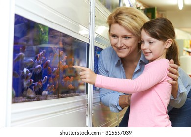 Mother And Daughter Choosing Goldfish In Pet Store