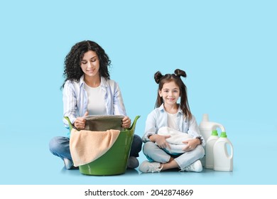 Mother and daughter with clean towels and detergents on color background - Powered by Shutterstock