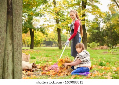 Mother and daughter cleaning up autumn leaves outdoors - Powered by Shutterstock