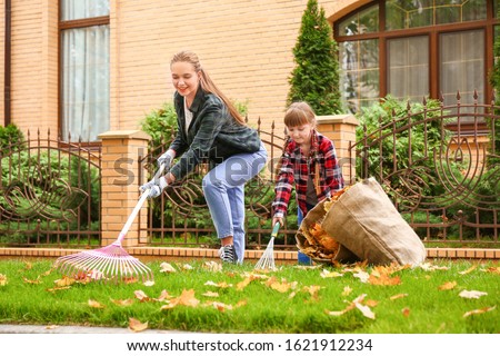 Mother and daughter cleaning up autumn leaves outdoors