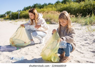 Mother and daughter are cleaning up the beach from plastic. save the planet concept. - Powered by Shutterstock