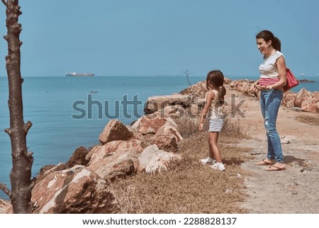 mother and daughter collecting and throwing rocks at the beach, Mother and daughters picking up rocks from wild roads and throwing them on the beach