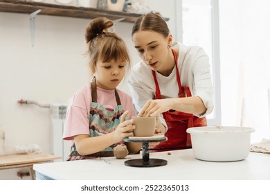 Mother and daughter create pottery together in a bright studio - Powered by Shutterstock