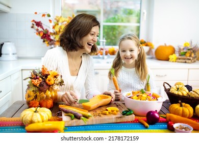 Mother And Daughter Cutting Pumpkin, Onion And Carrot, Cooking Soup For Autumn Meal. Mom And Child Cook Healthy Fall Vegetables For Family Halloween Season Lunch. Kids Cut Squash In Sunny Kitchen. 