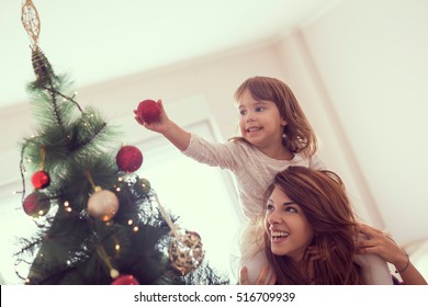 Mother and daughter decorating Christmas tree and having fun. Focus on the daughter