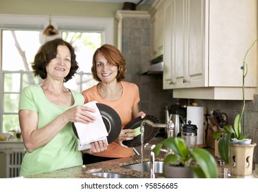 Mother and daughter doing dishes in kitchen at home
