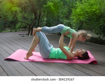 Mother And Daughter Doing Exercise Practicing Yoga Outdoors. Healthy Lifestyle