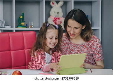Mutter und Tochter machen Hausaufgaben online. Fernstudium online. Schulmädchen mit digitalem Laptop Notebook und Hausaufgaben in der Schule. Mutter macht Hausaufgaben mit ihrer Tochter zu Hause