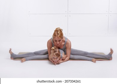 Mother Daughter Doing Yoga Exercise, Fitness, Gym Wearing The Same Comfortable Tracksuits, Family Sports Paired Woman Child Sitting On The Floor Stretching His Legs Apart In Different Directions Pose 