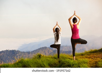 Mother and daughter doing yoga Tree pose at top of mountain - Powered by Shutterstock