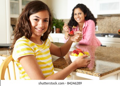 Mother And Daughter Eating Cereal And Fruit