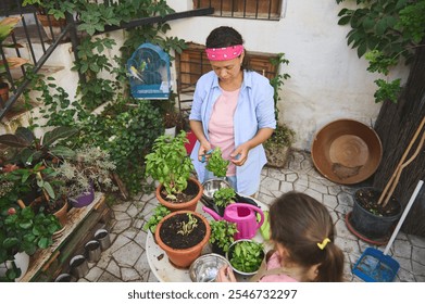 A mother and daughter engage in gardening, tending to herbs in a vibrant patio filled with potted plants. The scene exudes a sense of nature, family bonding, and tranquility. - Powered by Shutterstock