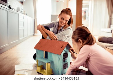 Mother and daughter engaging in arts and crafts painting a dollhouse