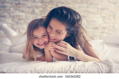 Mother And Daughter Enjoy In Bed At Home And Looking At The Camera. 