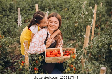 Mother and daughter enjoy a joyful moment while harvesting tomatoes in a vibrant garden, symbolizing family bonding and connection with nature. - Powered by Shutterstock